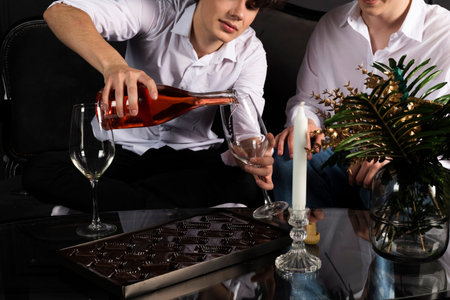 Two young guys celebrating with a bottle of champagne. Romantic evening of the gay couple. blonde...