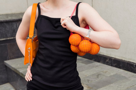 A beautiful fashionable young girl with distinctive orange elements in her clothing and makeup posing outdoor on the street.の写真素材