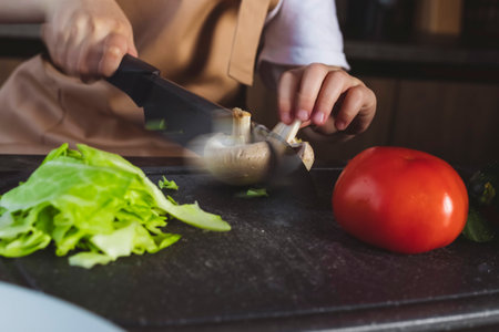 Little girl cooks on the kitchen, preparing ingredients, cutting vegetables, in motion shot.の写真素材