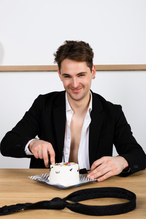 relaxed businessman casually celebrating his birthday, slices and eating a cakeの写真素材