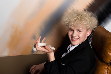 Stylish blonde haired young man and a Leucistic Ball Python. Pure white snake in businessman hands in the office.の写真素材