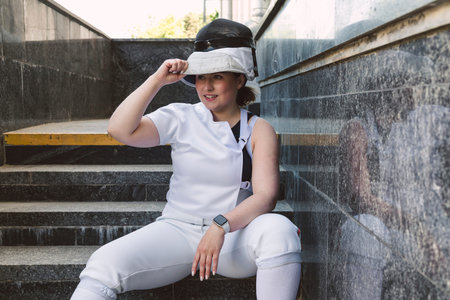 Female Fencer athlete wearing white fencing suit outfit and holding the sword, posing outdoorsの写真素材