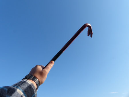 a hand holding a crowbar in the airの写真素材