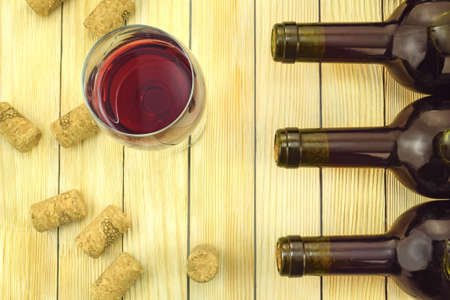   Image of glasses of red wine on the background of corks and bottlesの写真素材