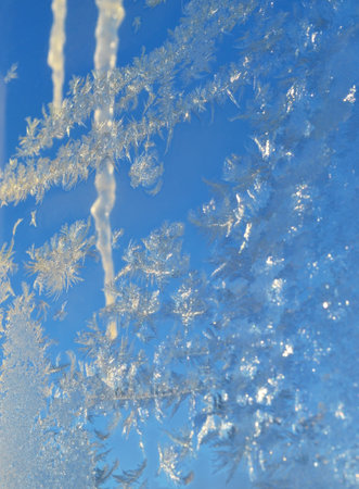 Frost tracery on glass on background of sky