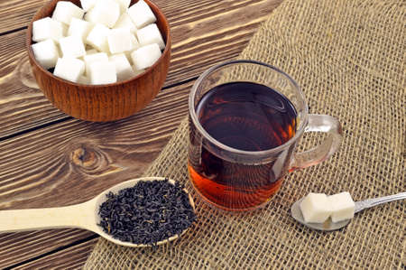Cup of black tea with slices of sugar on the tableの写真素材