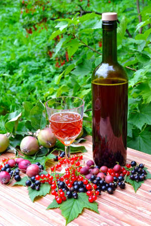 Photo bottle of red sparkling wine with a glass and berries on the tableの写真素材