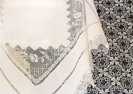 A beautiful white tablecloth, decorated with handmade lace, near bedspread is embroidered with a beautiful pattern of dark blue silk threads.の写真素材