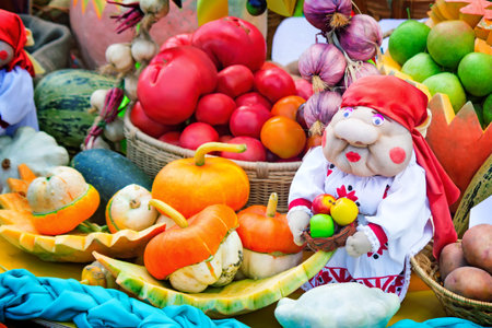On display for sale at the fair are a variety of vegetables: pumpkin, onions, beets, zucchini , tomatoes, garlic. Next to it is a figure of fun women.の写真素材