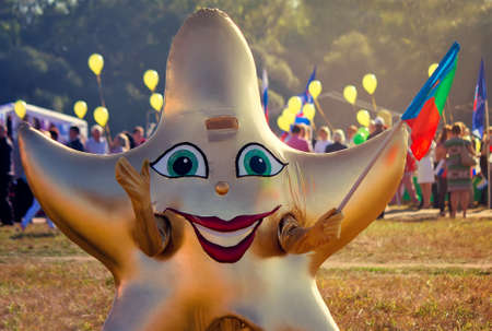 Depicts a man in a funny costume in the form of a star with a flag in his hand at the festival.の写真素材