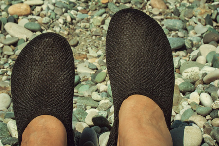 Comfortable black Slippers on the feet of the woman swimming and movement on the rocky beach.の写真素材