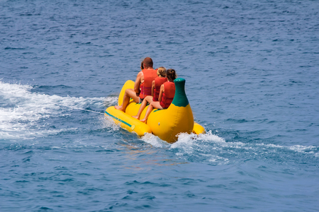 On inflatable mattress original shape in the form of banana take a walk on the sea man, two girls and a boy.の写真素材
