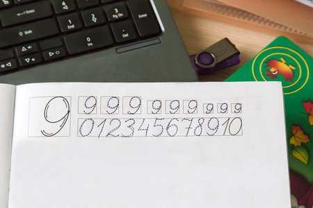 On the table lay a notebook in which the student learns to write the numbers.