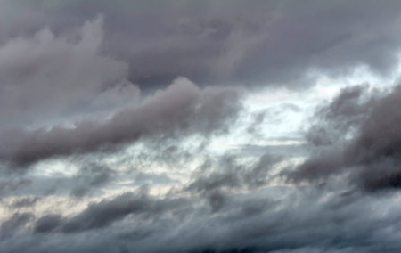 Dark rain clouds cover the autumn sky, leaving only small areas of bright blue sky.