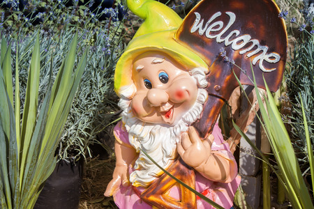 Hilarious funny, smiling dwarf with a white beard, digs earth and invites in your gardenの写真素材