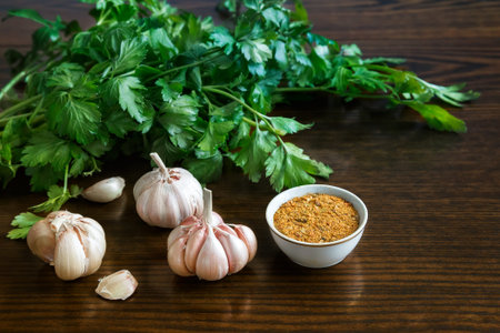 On the table lay the parsley leaves, spices and garlic. ( Photo in the style of dark key).