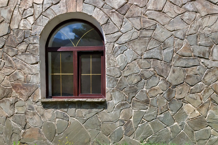 Detail of the facade with the window of a house in the mountains of natural stone of different size and shape.の写真素材