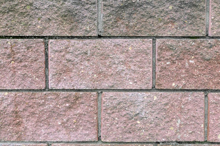 Fragment of brick walls, painted in pink and held together with cement mortar. Presents closeup....