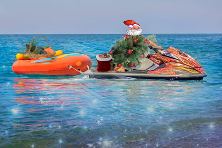 Christmas beach: a man masked as Santa Claus on a water scooter with Christmas tree and gifts is moving to the beach.の写真素材