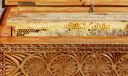 In a carved wooden box are a honeycomb with honey. Sold at the fair.
