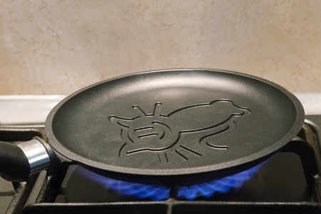 On fire of the gas stove heats up a cast iron frying pan for pancakes with ceramic coating.の写真素材