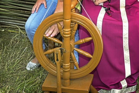 Old wooden spinning wheels and a woman in national dress.の写真素材