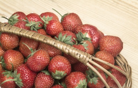 Red ripe strawberries with green leaves in a wicker basket. Submitted close-up.の写真素材