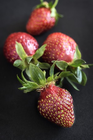 On a black background ripe red strawberry berries close-up.の写真素材