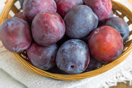 Large ripe plums in a wicker basket.