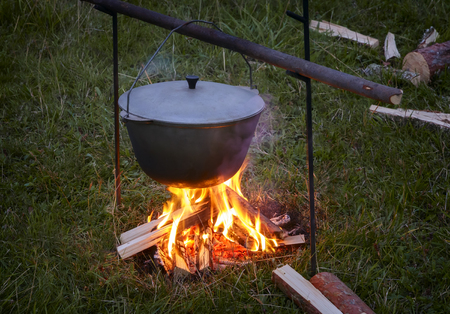 In a clearing in the woods in the evening on a fire in a pot cooking food.の写真素材