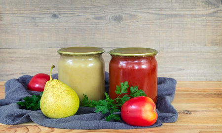 Pear puree and tomato juice are preserved in glass jars with sealed metal lids. Near lie pears and...
