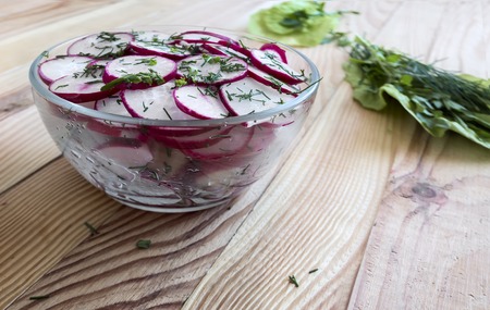 On the table, chopped salad radish in a glass bowl and arugula grass.の写真素材