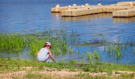 A little girl playing by the water on the river Bank.の写真素材