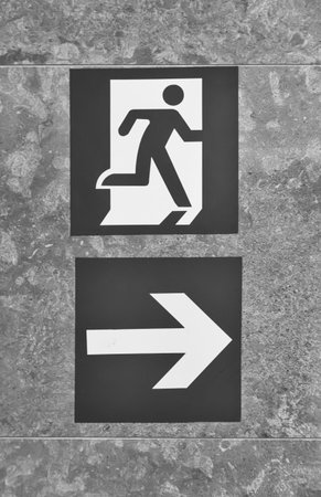 Pointer on the wall indicating the direction of movement to the exit of the room. Black and white...