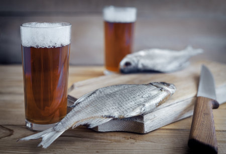 Two glasses of beer and dried fish .
