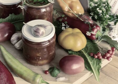 In glass jars Lecho of canned bell peppers and tomatoes, near fresh peppers and tomatoesの写真素材