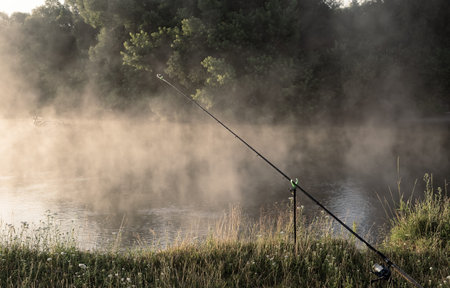 On the banks of the beautiful river over the water set fishing equipment to fish comfortably with...