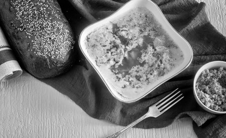 Pork jelly on the table. Next to bread and grated horseradish. Top view. Black and white image