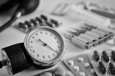 On the table is an apparatus for blood pressure measurement, which shows higher pressures. It's a hypertensive crisis. Near are medications to assist.の写真素材