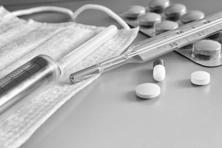 Medicines for the treatment of flu, colds on a red background: face mask, thermometer, pills, nose...