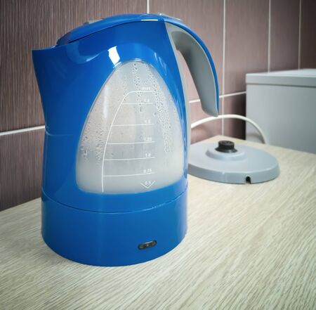 There is a modern blue electric kettle on the kitchen table.の写真素材