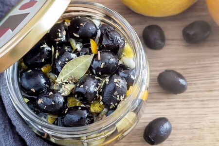 On a wooden table in a glass jar, pickled olives with spices, view from aboveの写真素材