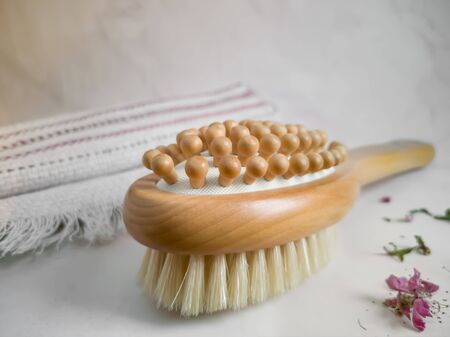 Anti-cellulite massage brush made of natural wood and natural bristles on the background of a linen towel. The concept of a healthy lifestyle. Lymphatic drainage massage.の写真素材