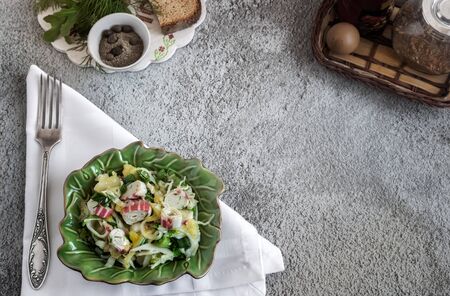 On the table in a ceramic plate vegetable salad of cabbage, pepper, green onions, crab sticks. Next to spices and bread . Top view, copy space.の写真素材