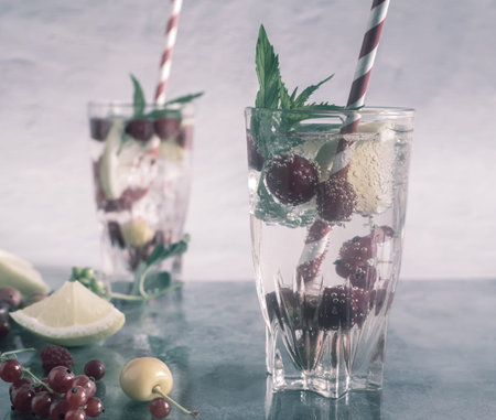 Refreshing summer drink with ice, berries and mint on a gray background