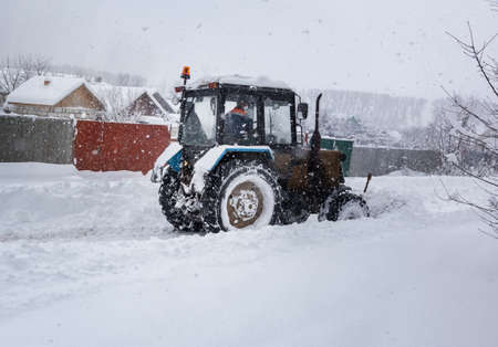 A small tractor clears the road from snowの写真素材
