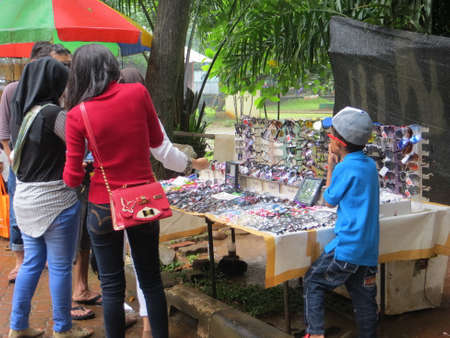 JAKARTA, INDONESIA - March 25, 2017: Young women buying sunglasses at street kiosk in Ragunan zoo.のeditorial素材