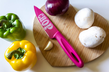 Food preperation with a pink knife, chopping board and vegetablesの写真素材
