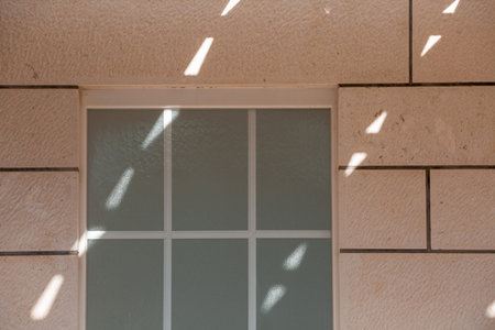 Pastel color tile wall of building facade with window and dotted lines of sunlight