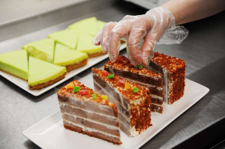 Confectioner is decorating cake red velvet in kitchenの写真素材